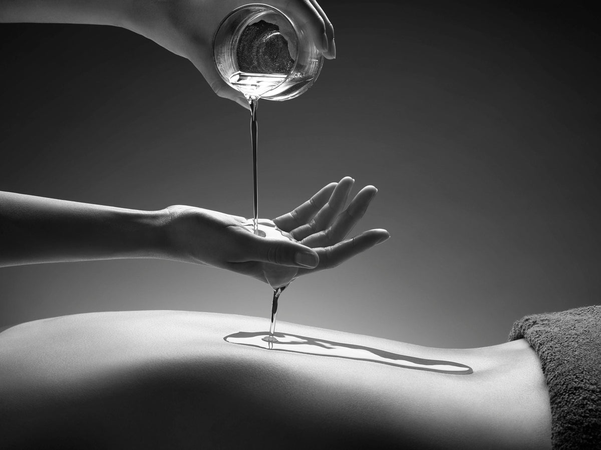 Huile de massage versée sur le dos d'une cliente