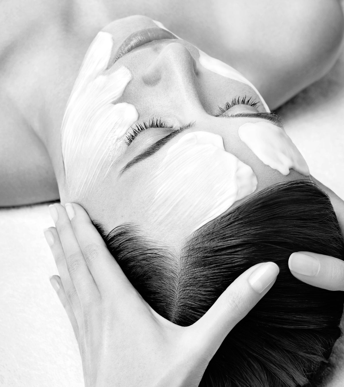 Mains d'une esthéticienne modelant le visage d'une cliente